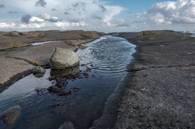 Su birikintisi kayalar arasında denize yol açar.