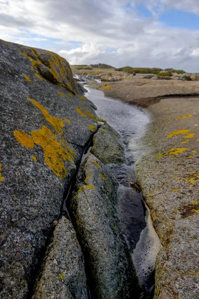 Su birikintisi kayalar arasında denize yol açar.