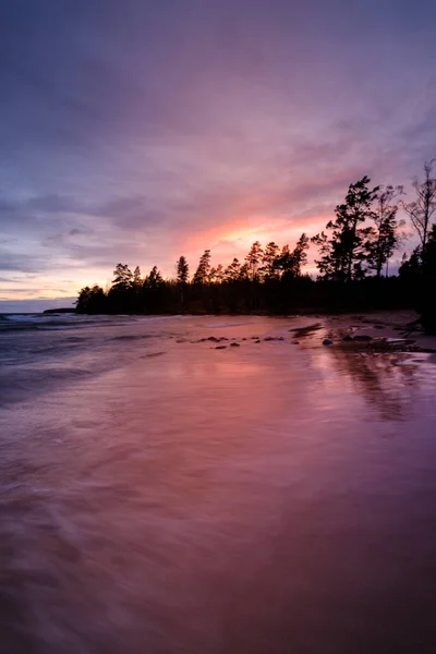 Pôr do sol colorido atrás da floresta e com a praia em foregrou — Fotografia de Stock