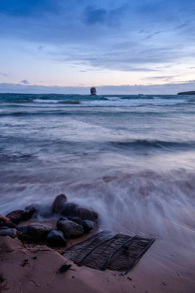 bir plajda ızgara ve kayalar ve arka planda küçük bir ada
