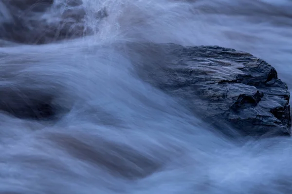 Primer plano de una ola que golpea sobre una piedra en el agua —  Fotos de Stock