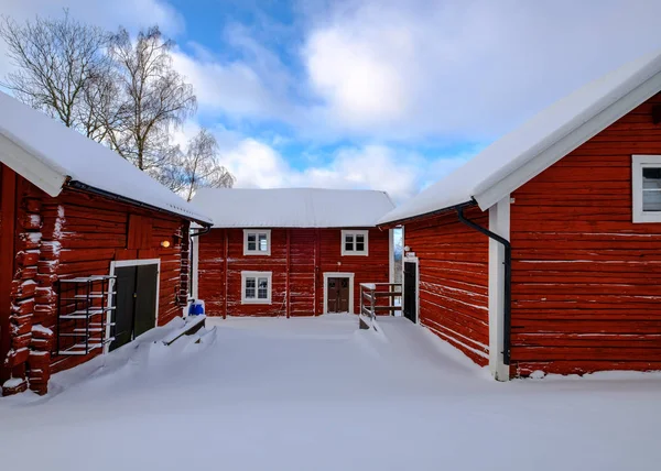 çatı ve zemin üzerinde kar ile üç kırmızı evler, mavi gökyüzü w