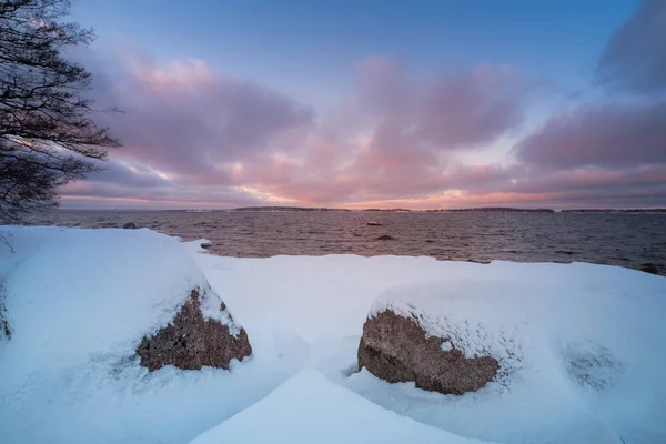 Duas pedras com neve em primeiro plano e a costa com sol — Fotografia de Stock