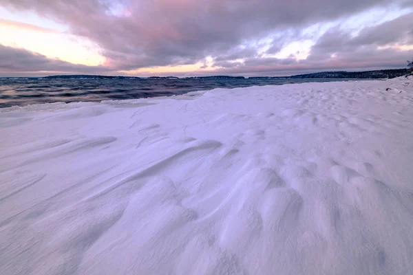 Neve em rochas na costa e pôr do sol no fundo — Fotografia de Stock