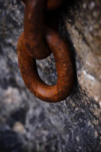 a large rusty chain hanging from a stone