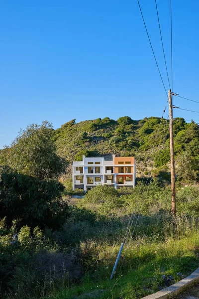 ön planda bir dağ ve ön planda elektrik direği ile eksik bir ev