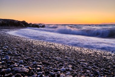 sahilde köpük ve arka planda gün batımı ile dalgalar