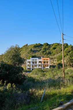 ön planda bir dağ ve ön planda elektrik direği ile eksik bir ev