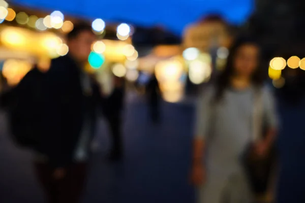 The whole picture is out of focus with two individuals in the foreground and street lights in the background