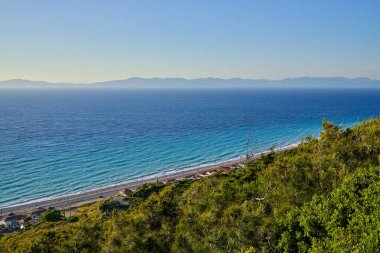 bulutsuz bir yaz akşamı altında orman ve deniz ile yamaç