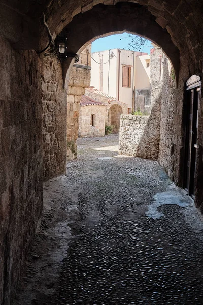 alley with cobblestones and stone arch, old buildings in the background