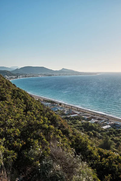 hillside with forest and sea below a cloudless summer evening