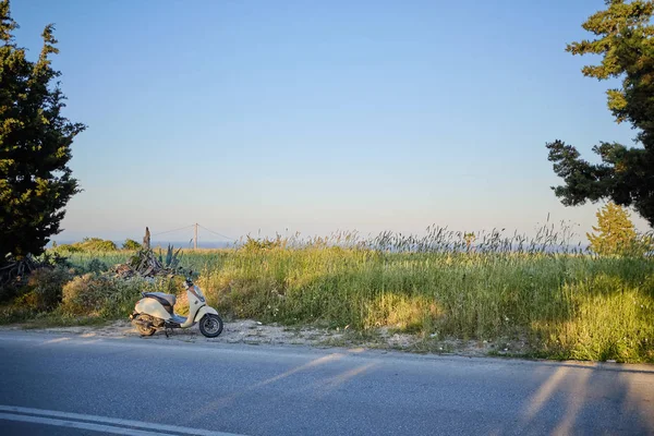 Vespa yol boyunca park, arka planda yeşil alan