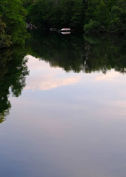 写真で最も遠い海岸にボートを持つ川の森と空の反射 — ストック写真