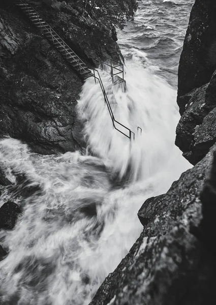파도는 각도에서 바위들이 주위를 둘러싸고 가운데 계단을 파도를 흐른다 — 스톡 사진
