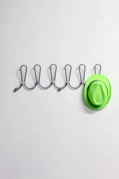 green hat on a clothes hanger on a white wall