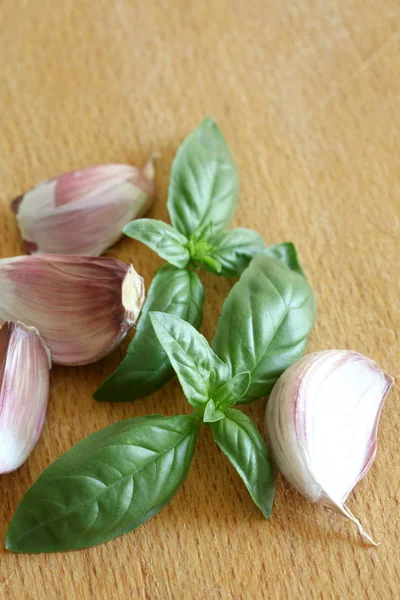 garlic cloves and basil leaves on a wooden cutboard