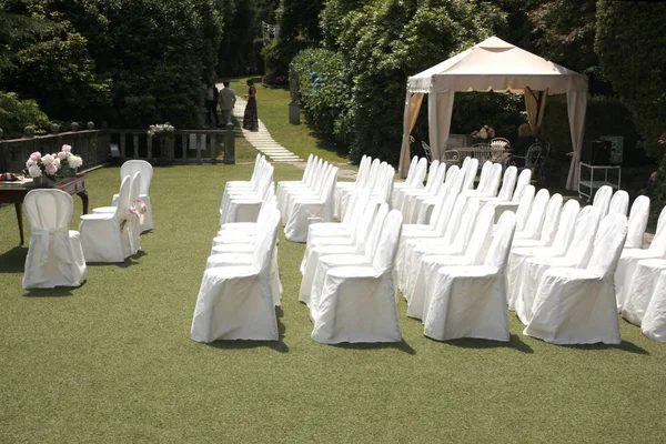 wedding ceremony outdoor set: line of white chairs with desk and chair for the merried and  the officier