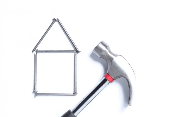 不動産の概念 あなたのテキストのためのコピースペースと白い背景に隔離された釘とハンマーで作られた家の形状 — ストック写真