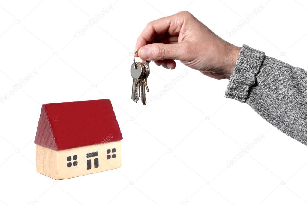 real estate concept: man's hand holding a key and a toy house isolated on white background with copy space for your text