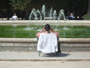 Kraliyet Sarayı, Paris, Fransa, 17 Ağustos 2018: Bir çeşmenin önünde sandalyede oturan kadın