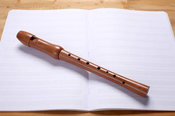 wooden flute and empty music score rest on a wooden table with copy space for your text