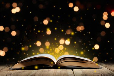 glitter ve bokeh ışıkları ile ahşap bir masa üzerinde sihirli kitap açmak ve metin için kopya alanı ile siyah arka plan