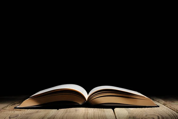 metin için kopya alanı ile ahşap bir masa ve siyah arka plan üzerinde kitap açık