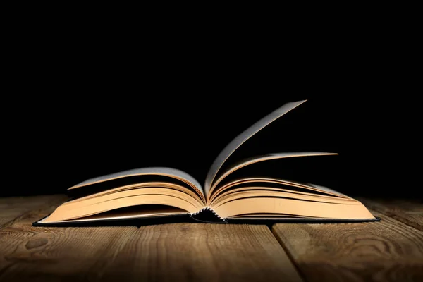 metin için kopya alanı ile ahşap bir masa ve siyah arka plan üzerinde kitap açık