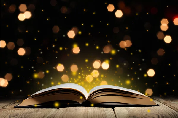glitter ve bokeh ışıkları ile ahşap bir masa üzerinde sihirli kitap açmak ve metin için kopya alanı ile siyah arka plan
