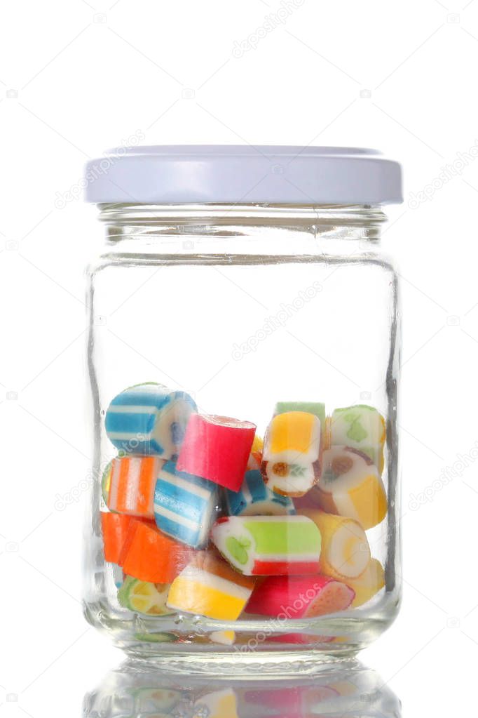 a glass jar half  full of colored candies with isolated on white background with clipping path and copy space for your text