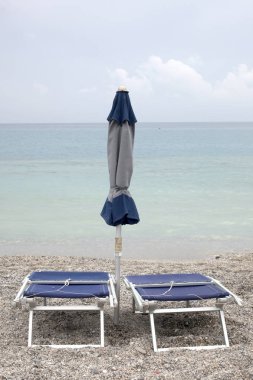 yaz sonu konsepti: metin için kopya alanı ile bir plajda yakın güneş şemsiyesi ve şezlong