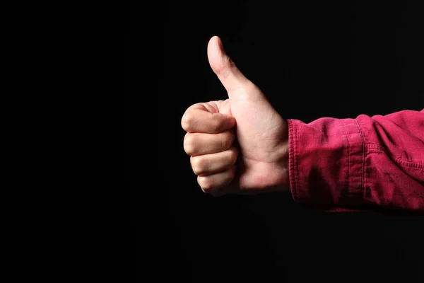 man hand makes thumb up gesture isolated on black background with copy space for your text