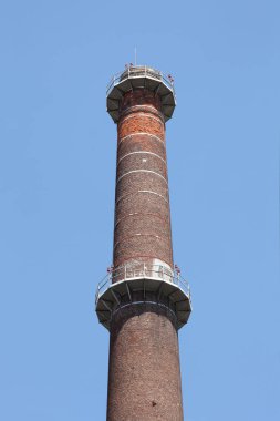  Mavi gökyüzünde uzun endüstriyel baca. Metnin için kopyalama alanı var.