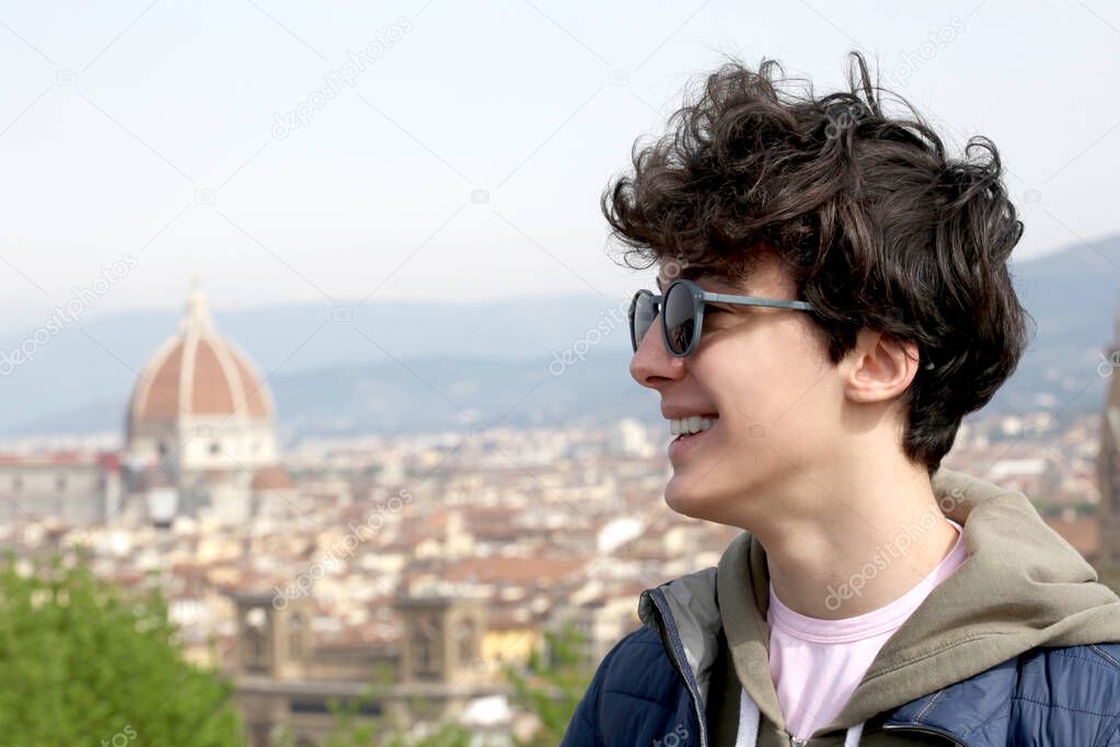 portrait close up of a smiling male teenager with the city of Florence on the background with copy space for your text