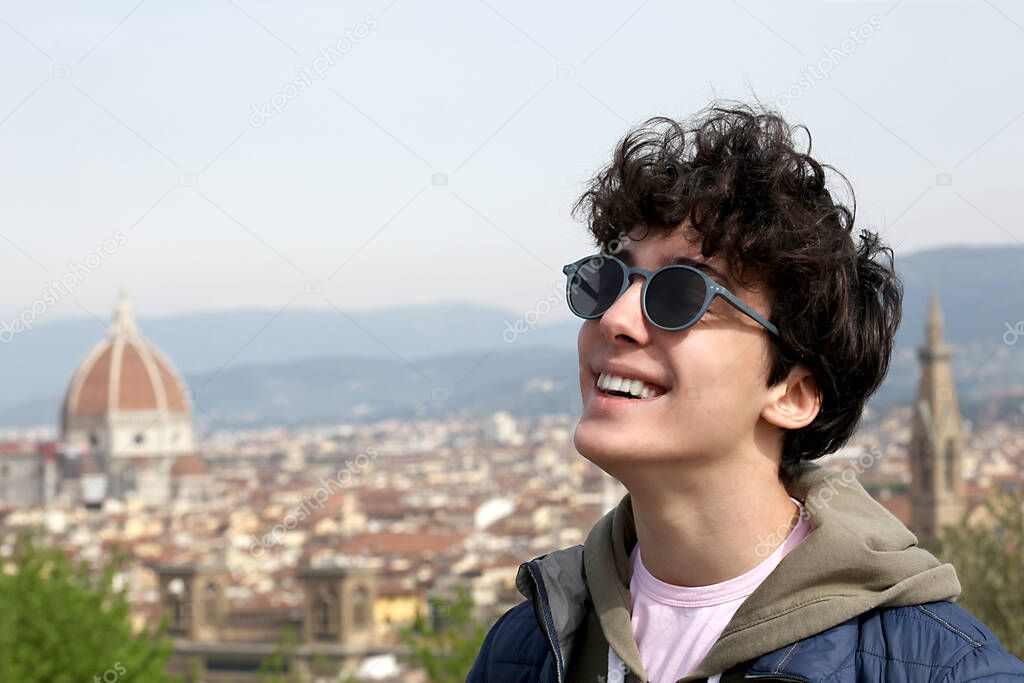 portrait close up of a smiling male teenager with the city of Florence on the background with copy space for your text
