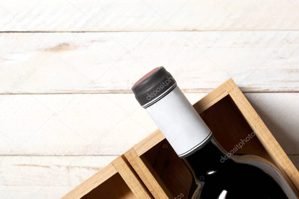 red wine bottle in a wooden box rest on a white wooden table with copy space for your text