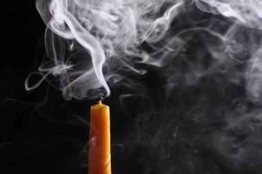 Metnin için kopyalama alanı olan siyah arkaplanda izole edilmiş dumanı olan bir mumu kapat