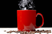 červený šálek kávy a kávových zrn odpočívat na mramorovém stole na černém pozadí s kopírovacím prostorem pro váš text