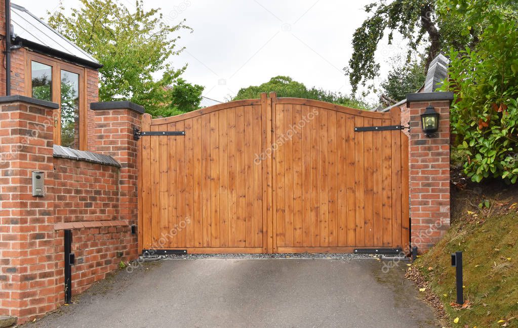 Wooden gate on the driveway of a residential house with keypad operated lock