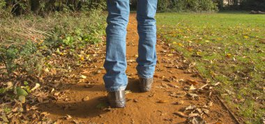 Bir adam Jeans sonbahar sırasında düşen yapraklar kapalı bir yol boyunca girer