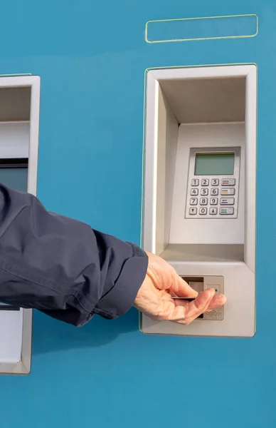 A person using a credit card in a self service ticket machine  to purchase a travel  ticket