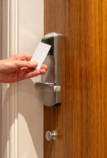 A man opens a hotel door using a contact less key card and sees a green light confirming the door is open