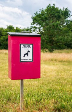 Şehir parkındaki bir direkte imzalanmış kırmızı bir köpek çöplüğü.