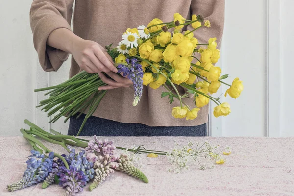 woman florist making flower bouquet on table