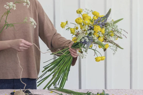 woman florist making flower bouquet on table