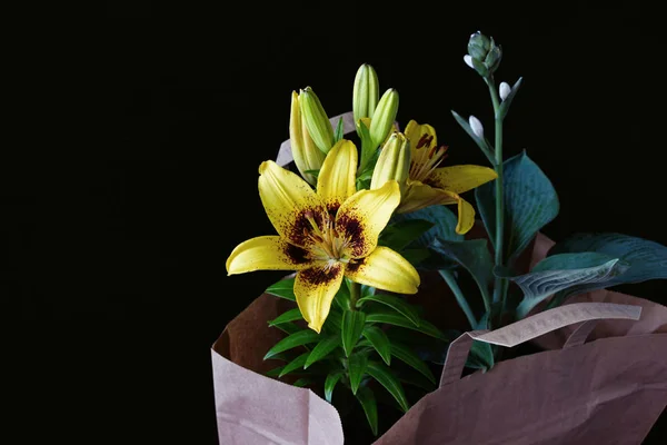Sárga Liliom Virág Zöld Növény Papírzacskóba Fekete Háttér — Stock Fotó