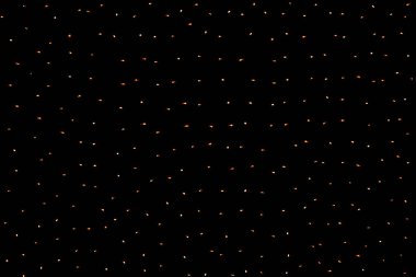 Siyah arka planda bir çelenkten parlayan birçok küçük turuncu ışık. Karanlıkta yanan ampuller