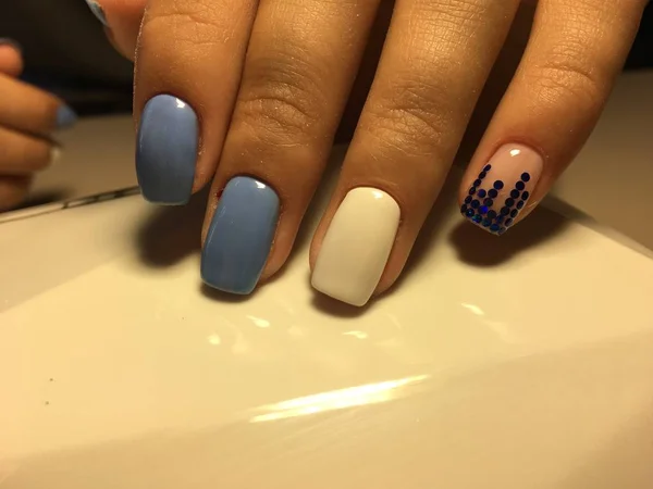 fashionable blue manicure with white design and blue pawns on a light background