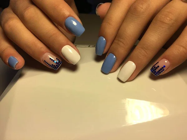 fashionable blue manicure with white design and blue pawns on a light background